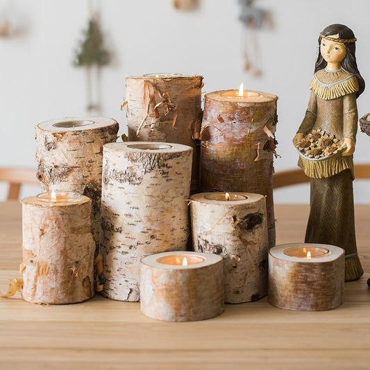 Set of birch bark candles on a wooden surface with a decorative figurine in the background.