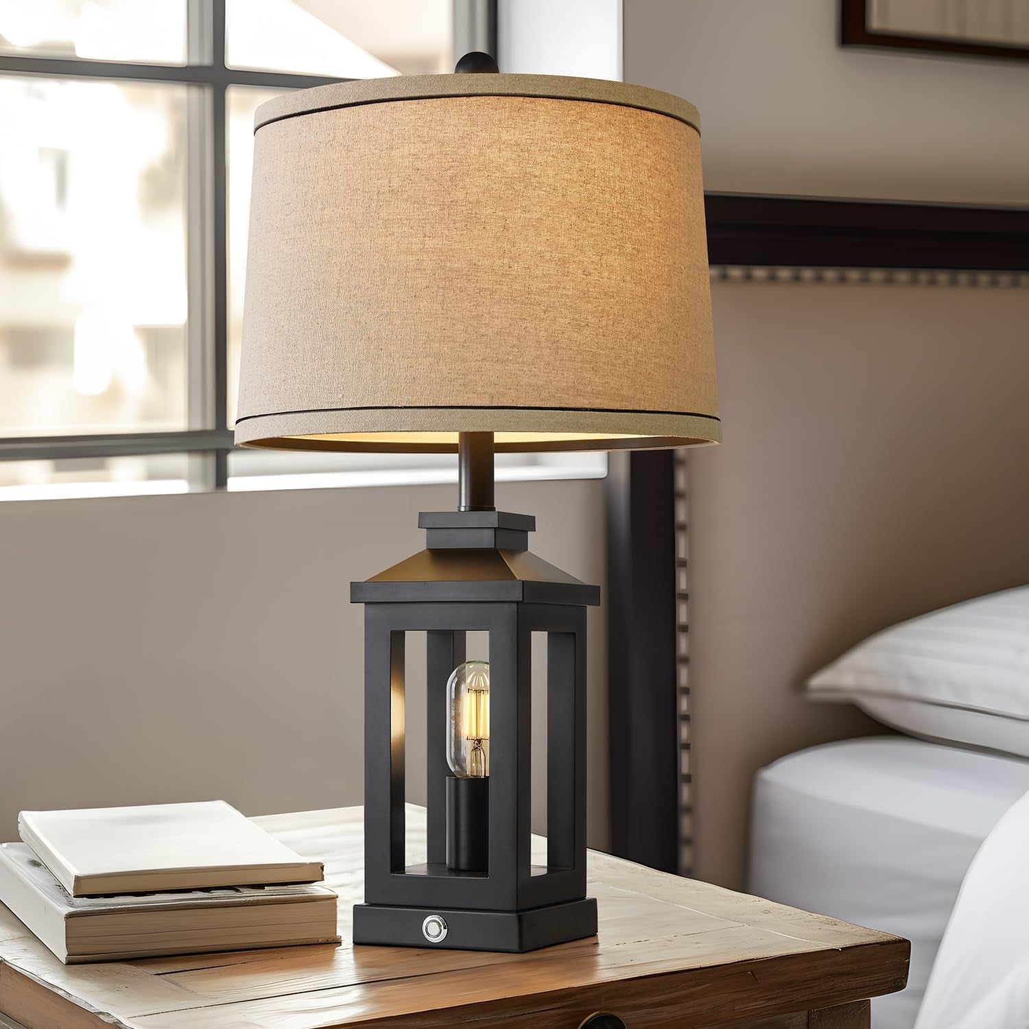 Table lamp with a beige shade on a wooden table in a room setting.