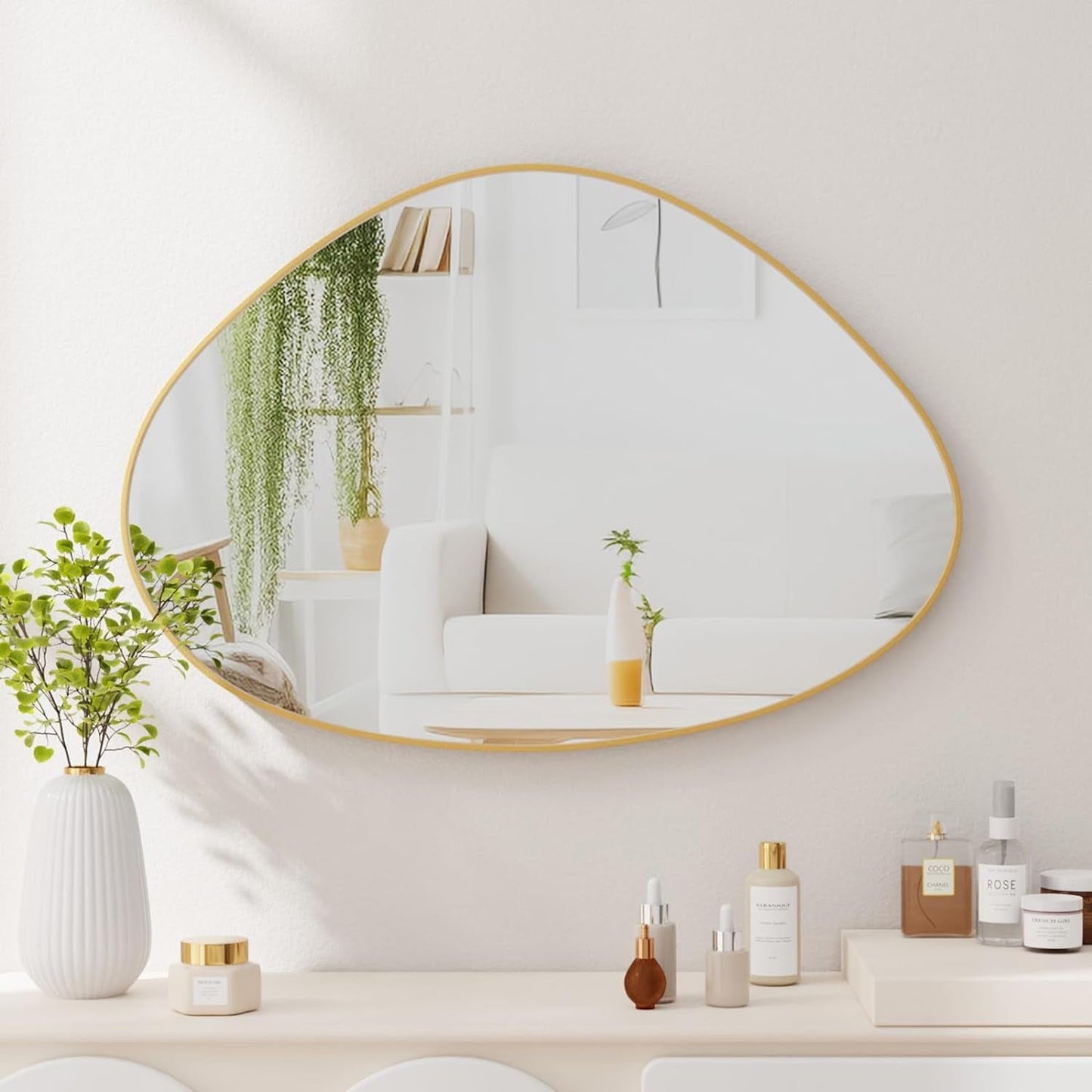 Round gold-framed mirror on a wall with decorative items below
