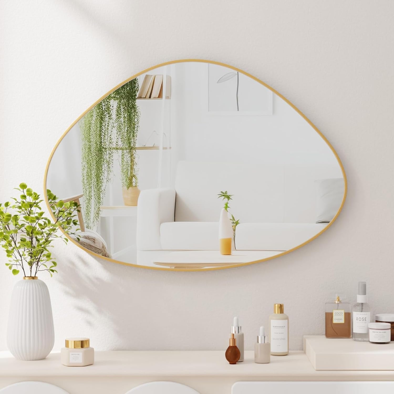 Round gold-framed mirror on a wall with decorative items below