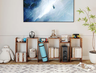 Wooden bookshelf with various items in a room with a large TV on the wall.