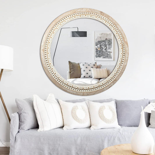 Decorative round mirror with intricate frame above a gray sofa in a living room.