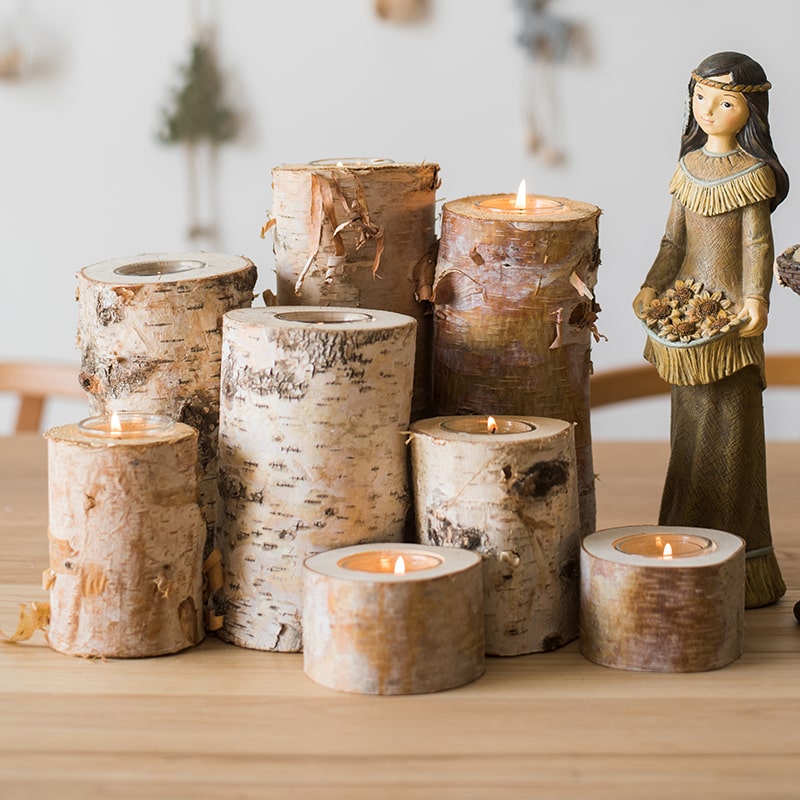 Set of birch bark candles on a wooden surface with a decorative figurine in the background.