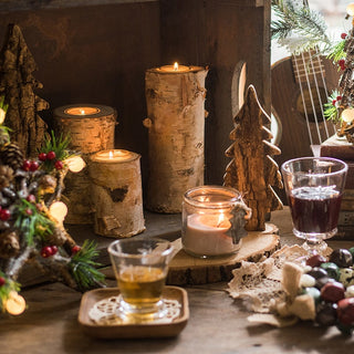 Decorative setting with candles, glasses, and Christmas-themed decor on a wooden table.