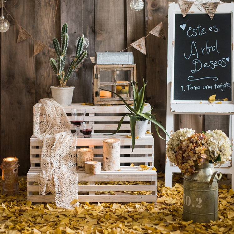 Decorative setup with wooden crates, plants, and a chalkboard sign against a wooden wall.