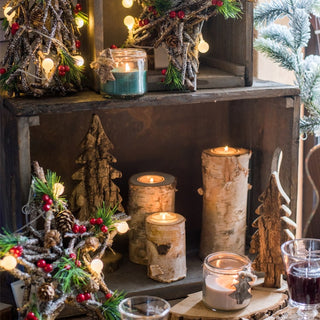 Decorative setup with candles, wooden ornaments, and Christmas trees on a rustic shelf.