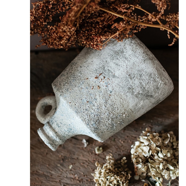 Vintage-style ceramic bottle with dried flowers on a wooden surface