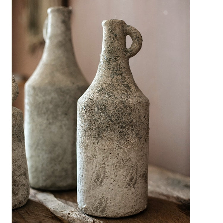 Two textured stone bottles on a wooden surface with a neutral background