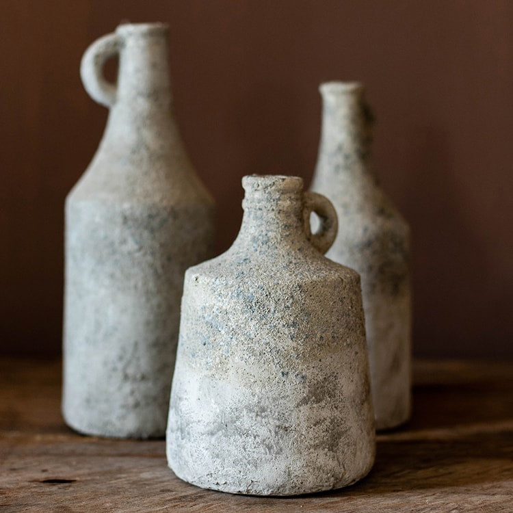 Three rustic ceramic bottles on a wooden surface with a brown background