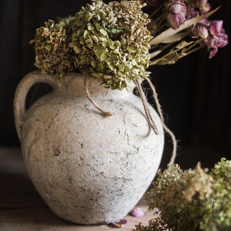 Vintage-style vase with dried flowers on a dark background
