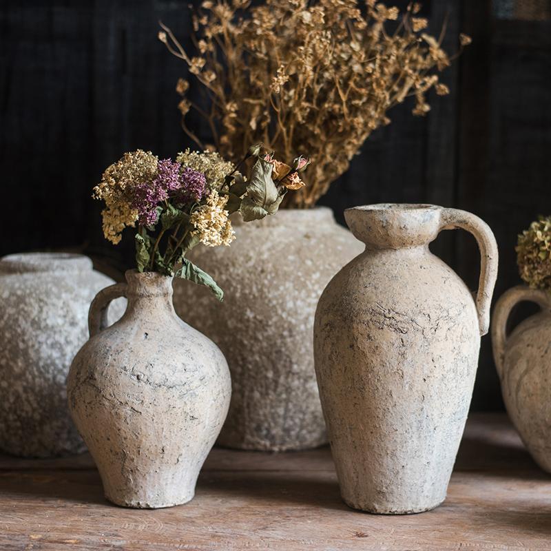 Collection of rustic clay vases with dried flowers on a wooden surface