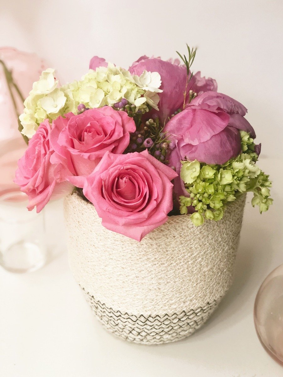 Bouquet of pink and green flowers in a textured vase on a light background